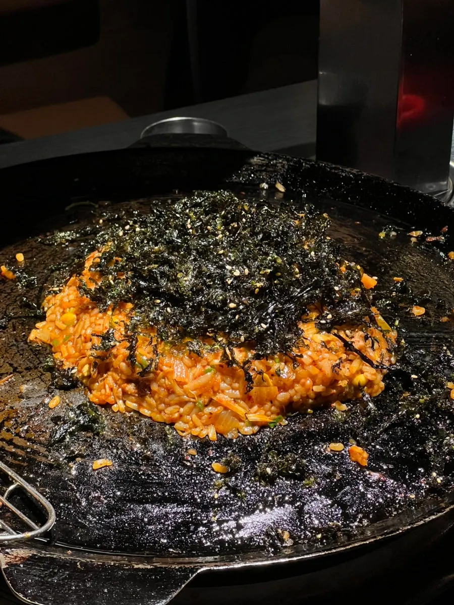 A spoonful of fried rice with a runny egg yolk popped