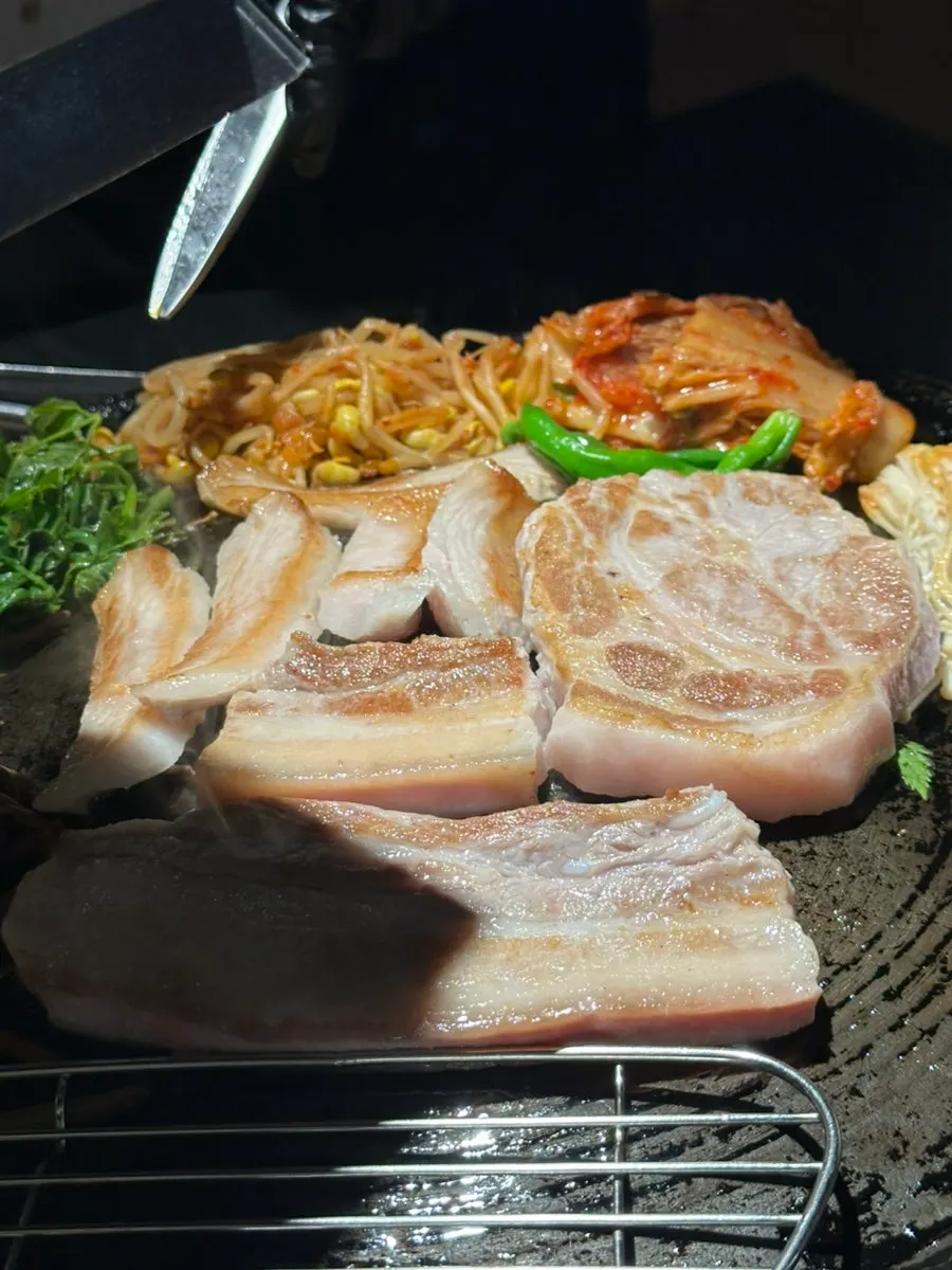 Meat and vegetables cooking together on the cauldron lid