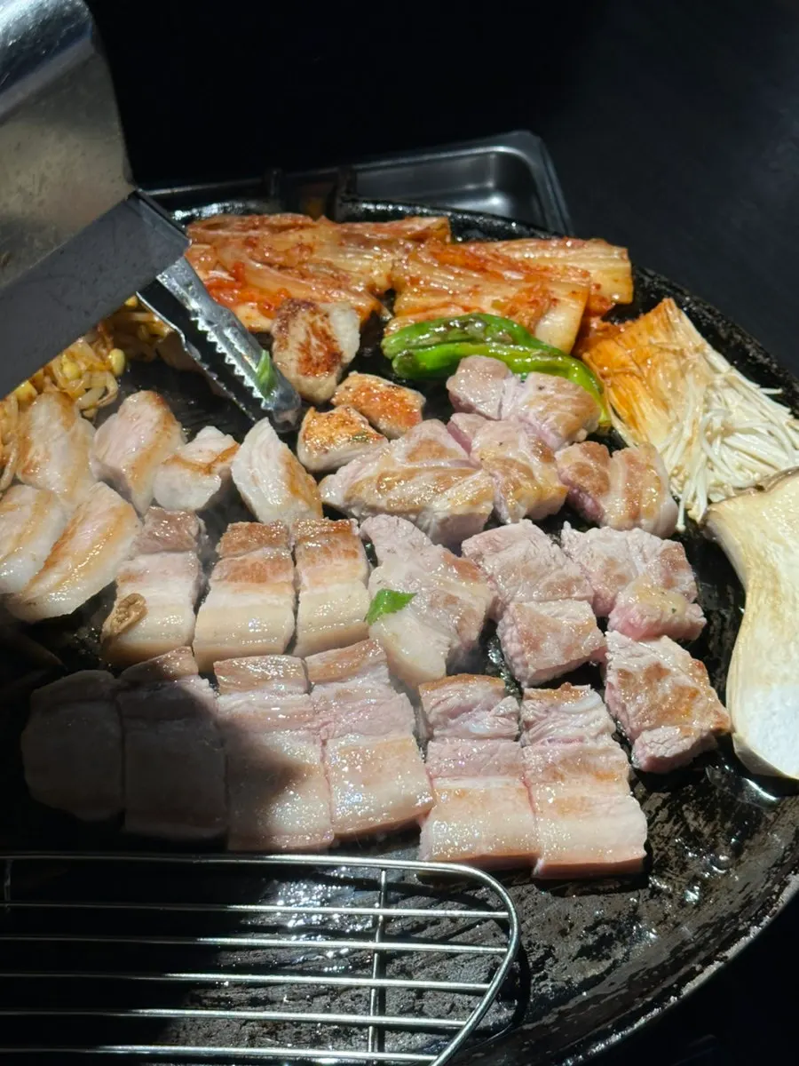 Staff member grilling meat on the cauldron lid
