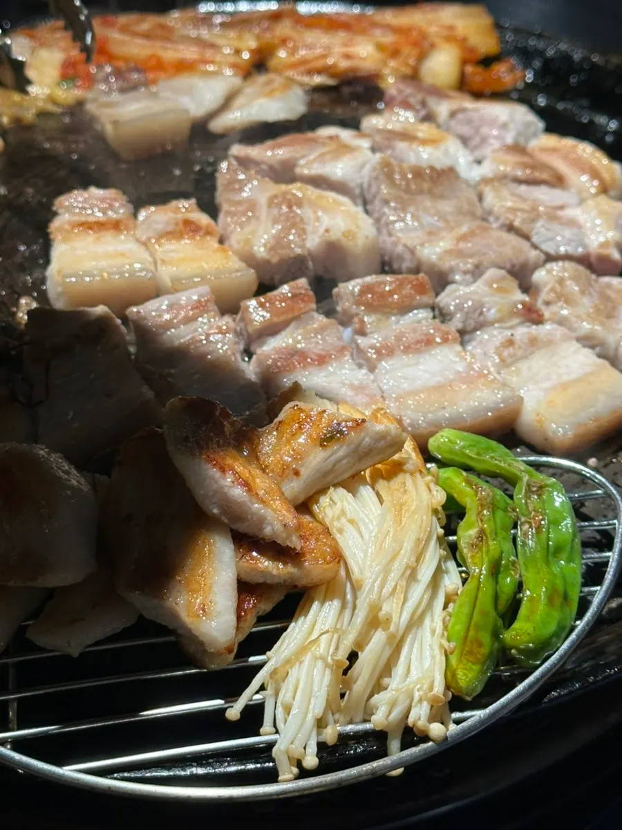 Meat being flipped with tongs while grilling