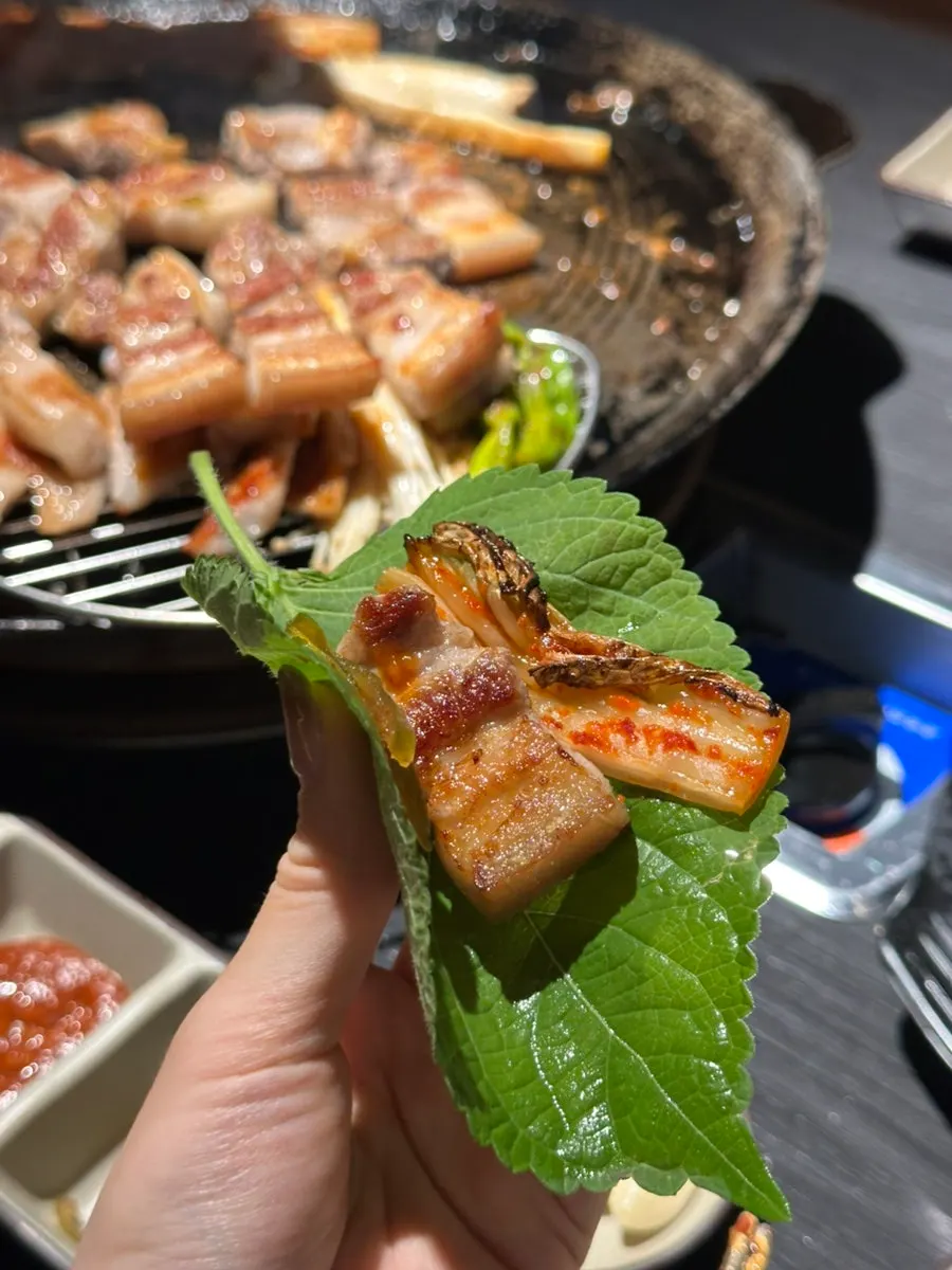 Meat wrap topped with grilled minari and kimchi