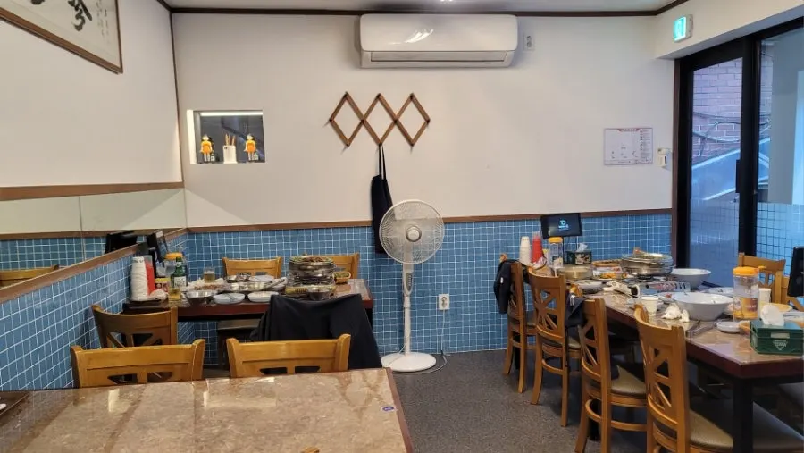 파란 타일과 원목 테이블이 놓인 매장 내부