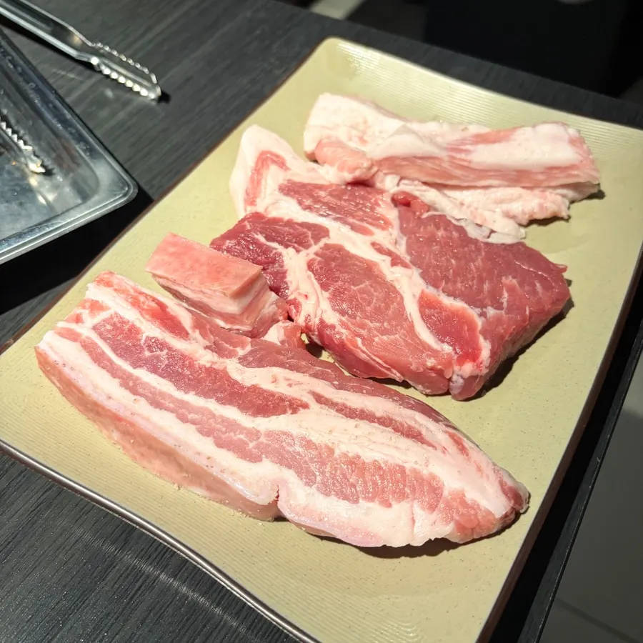 Plate of raw pork belly with skin, pork jowl, and pork neck