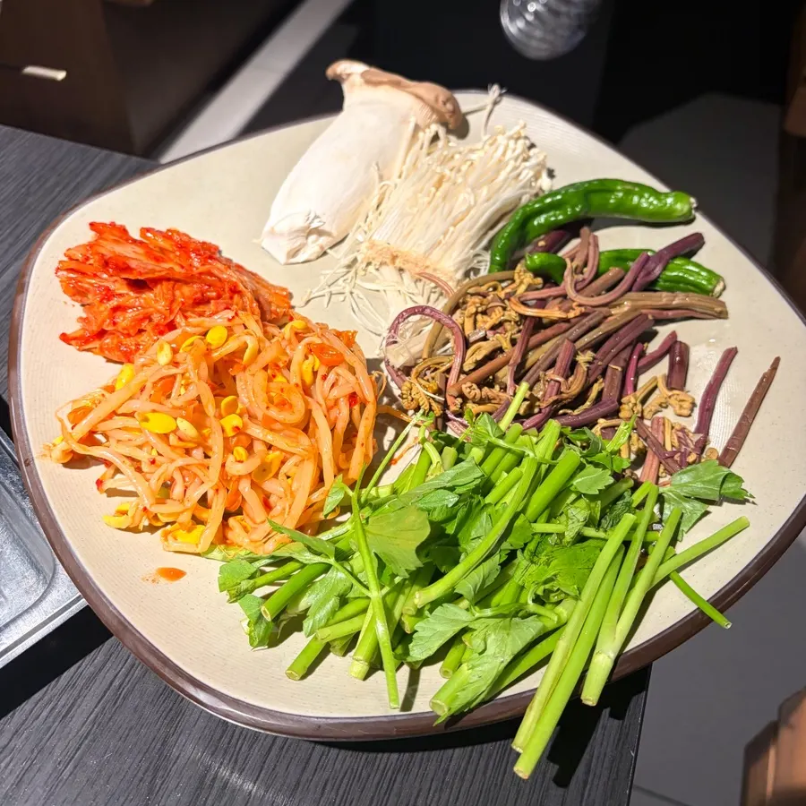 Cauldron lid topped with bean sprouts, bracken, minari, and mushrooms