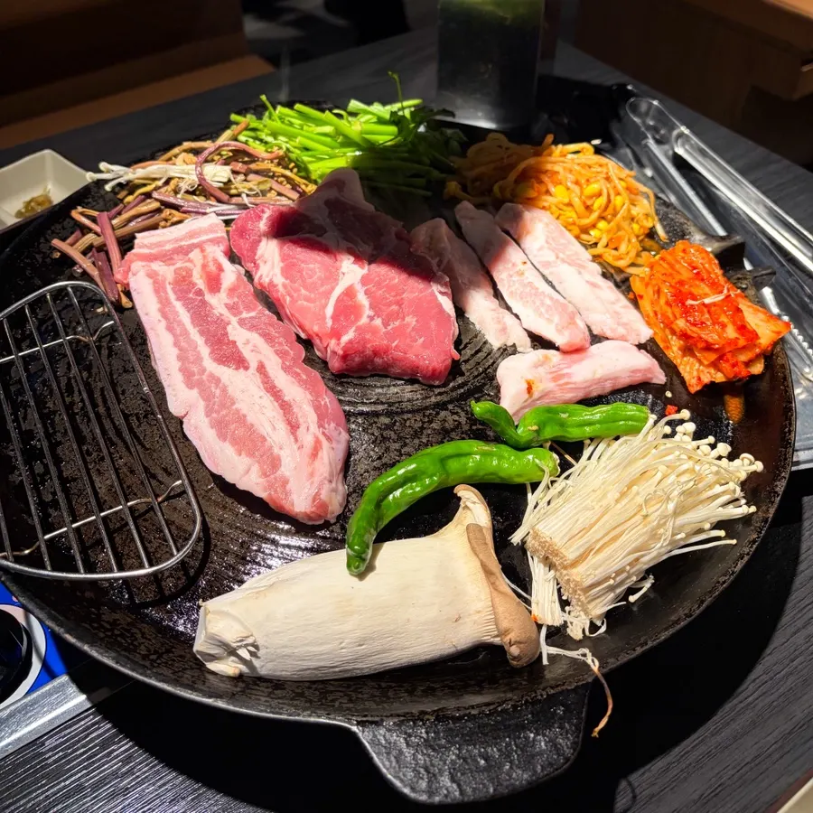 Staff member grilling meat and vegetables on the cauldron lid