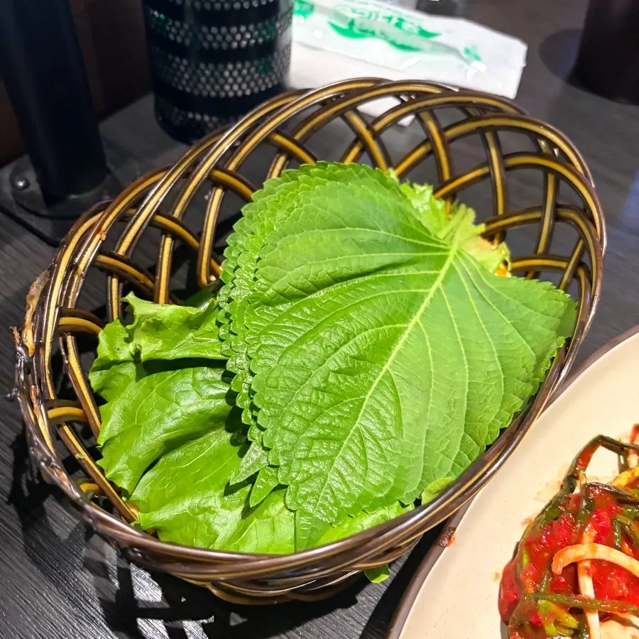 Side dishes including perilla leaves and lettuce at Sodangkkae O-gyeopjip
