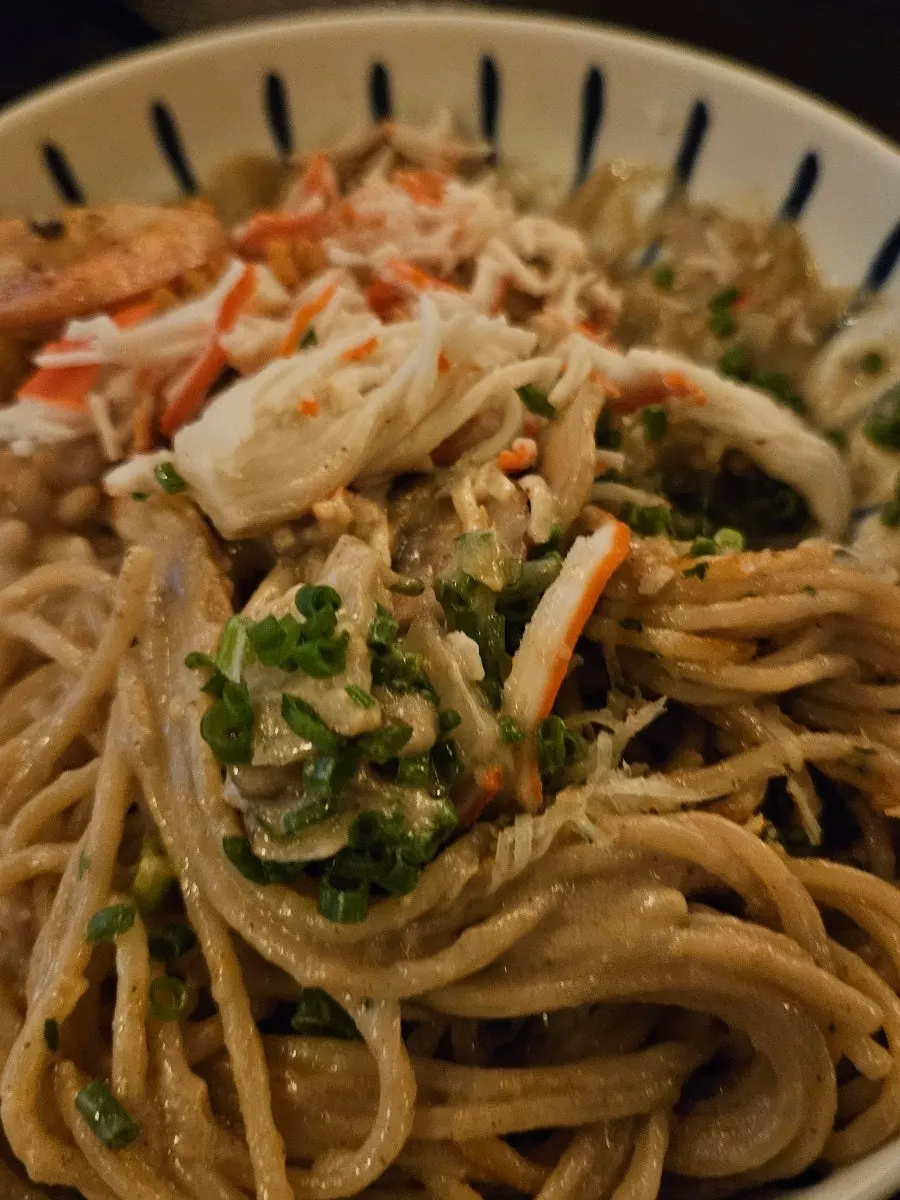 A bite of crab tomalley pasta with toppings mixed in
