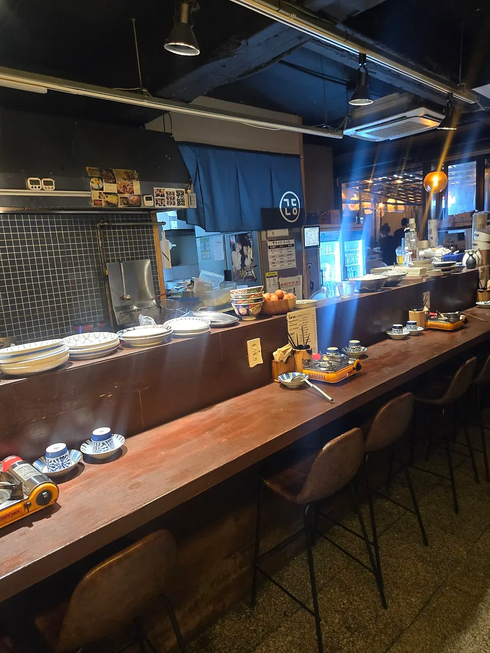 Long dachi bar seats stretching out in front of the open kitchen