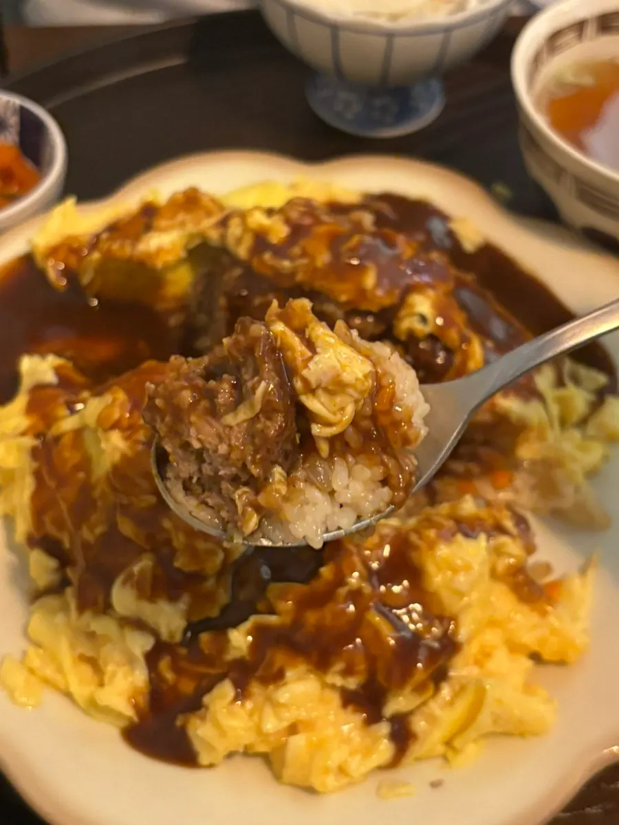 A spoonful of hambagu omurice with sauce poured on