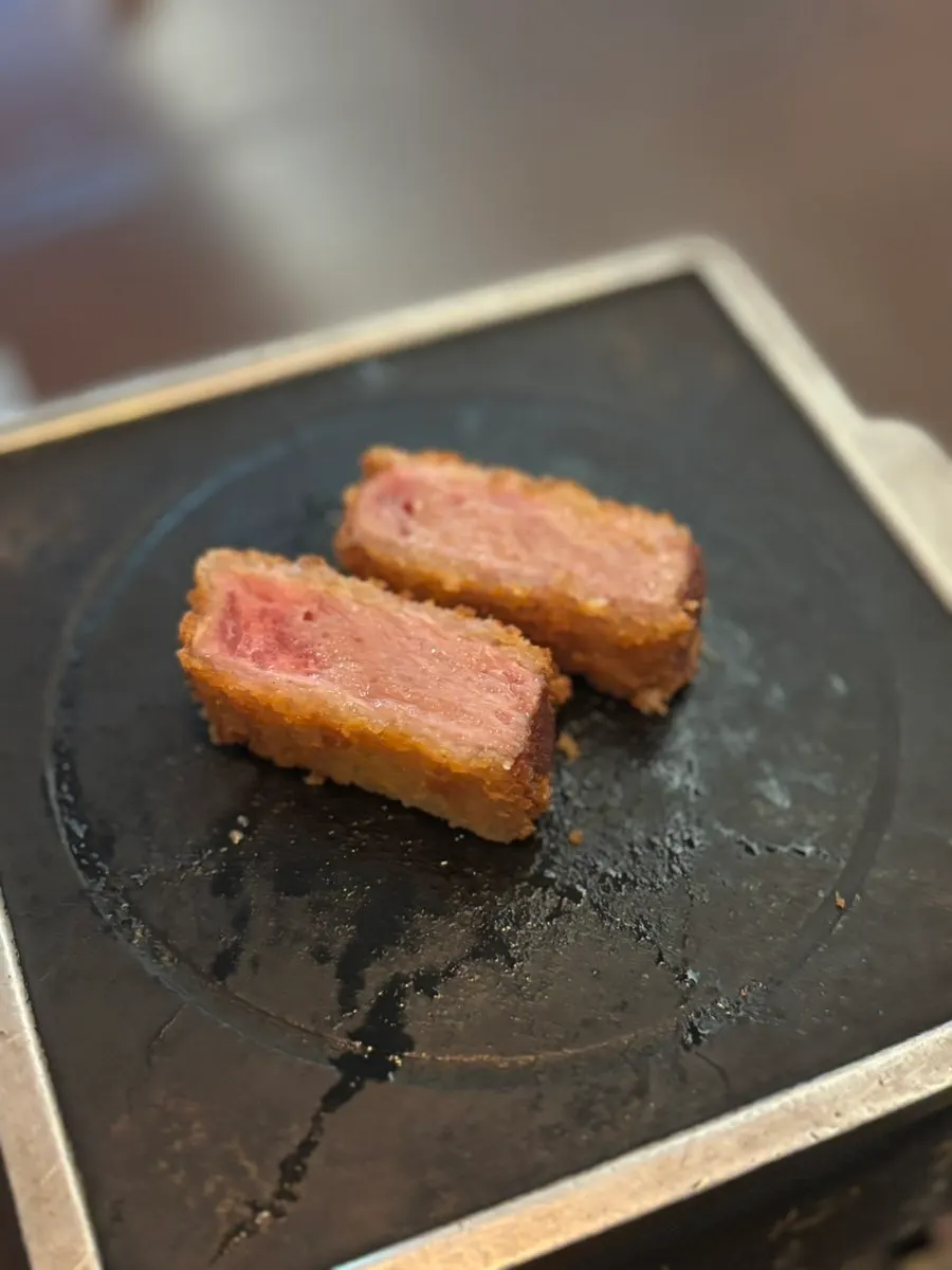 A piece of gyukatsu on the hot grill plate