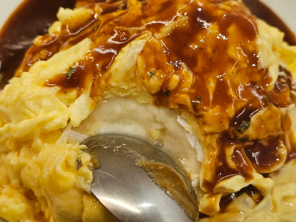 A spoonful of brie cheese omurice topped with sauce