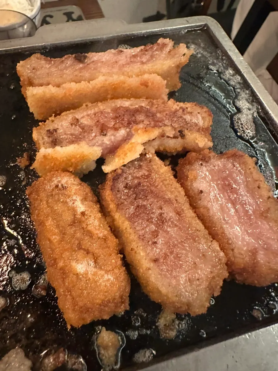 A piece of gyukatsu being grilled on the brazier