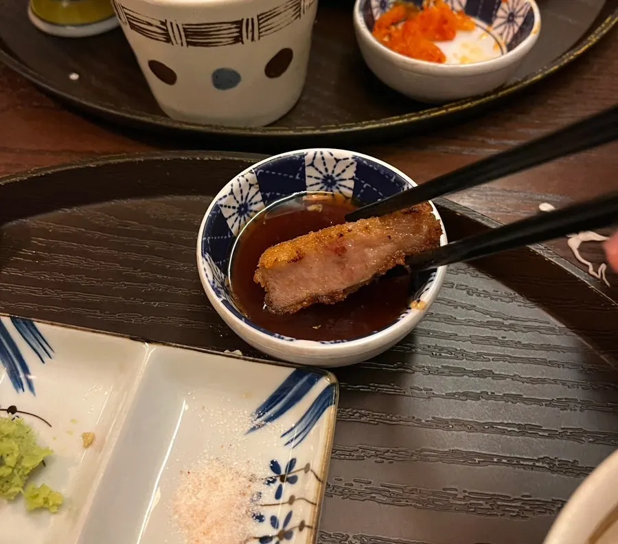 A piece of gyukatsu dipped in ginger sauce