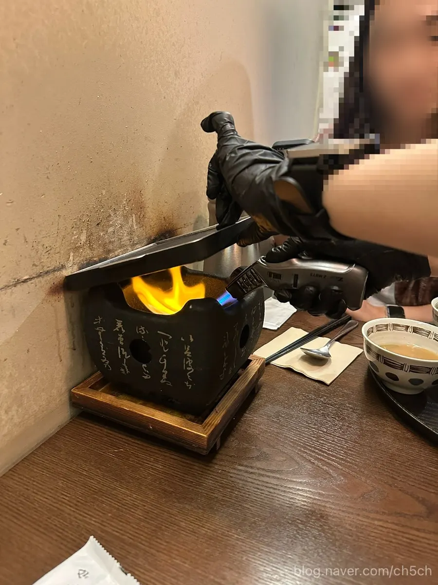 Staff member torching the gyukatsu grill