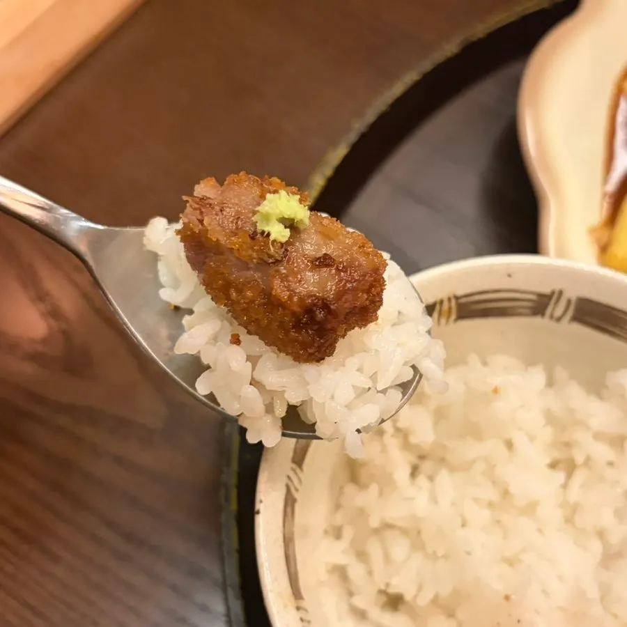 A piece of gyukatsu topped with pink salt and wasabi