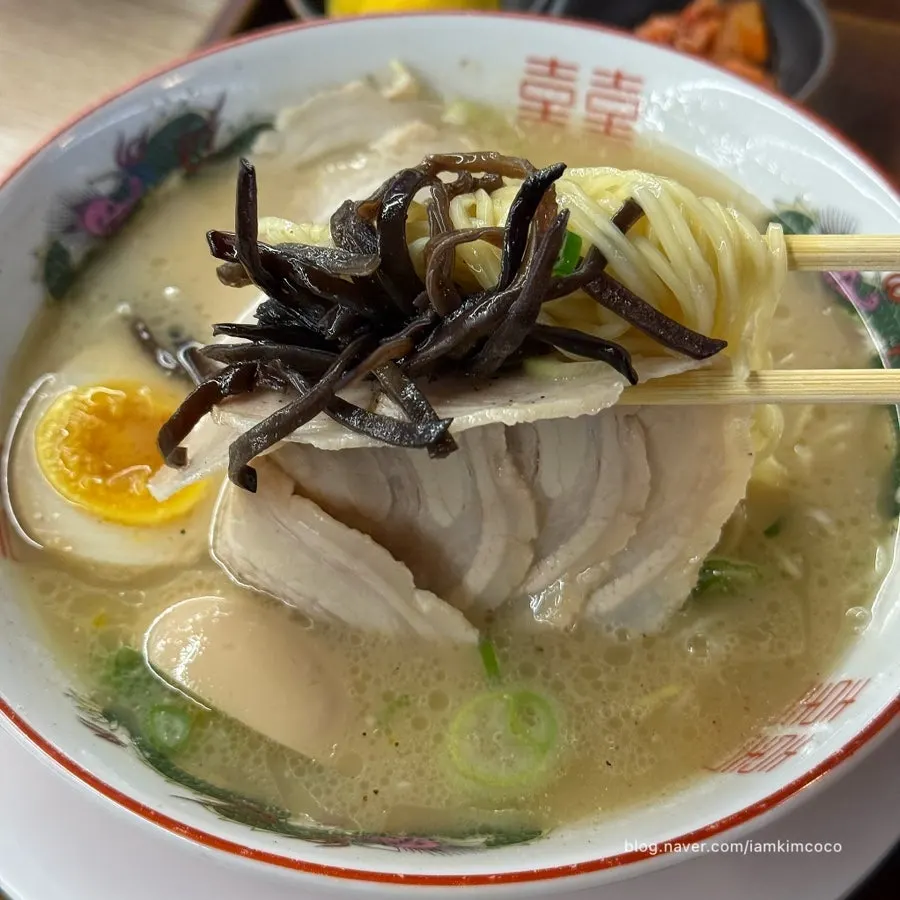 Chashu and noodles lifted together with chopsticks