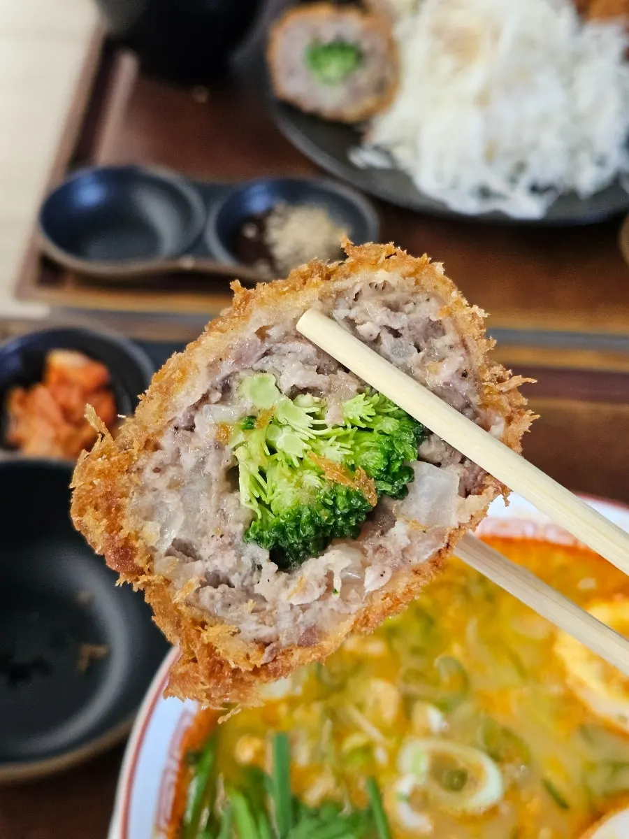 Broccoli and eggplant visible inside the menchi katsu