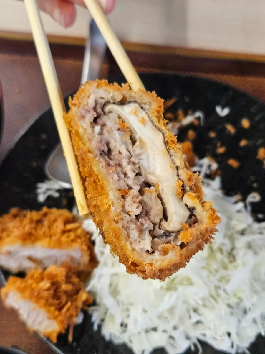 A piece of menchi katsu with shiitake mushroom inside