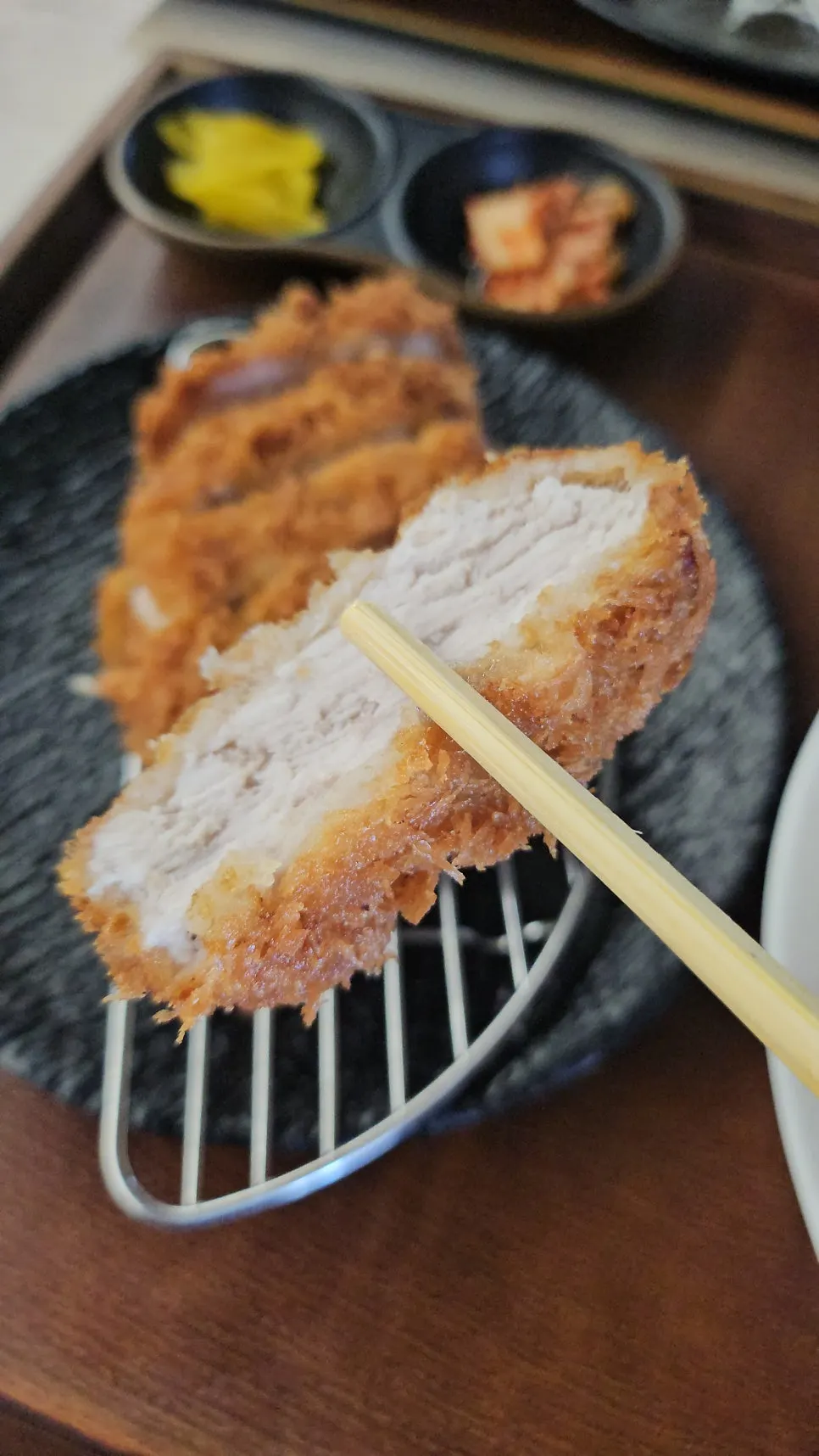 젓가락으로 집은 두툼한 돈카츠 단면