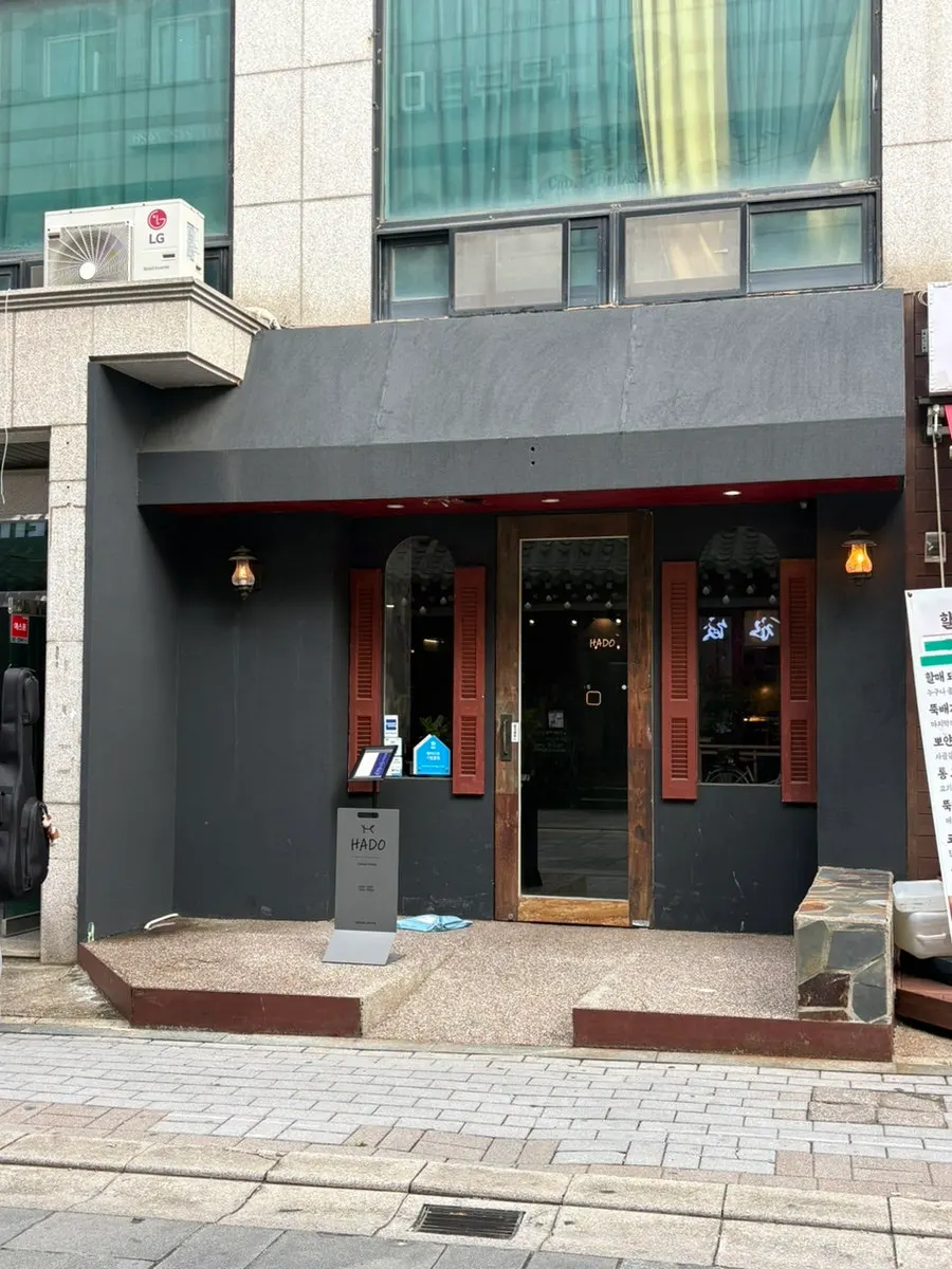 Hado's exterior with dark tones and a wood-toned door
