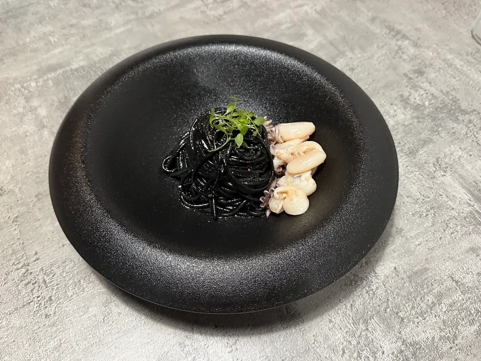 Squid ink oil pasta topped with cuttlefish
