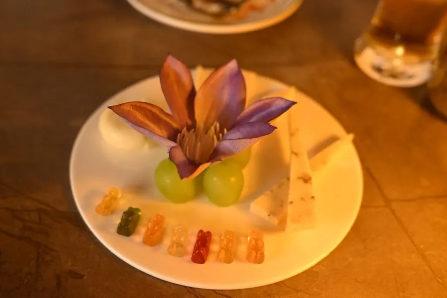 BTS meal cheese platter topped with a purple flower and gummy bears