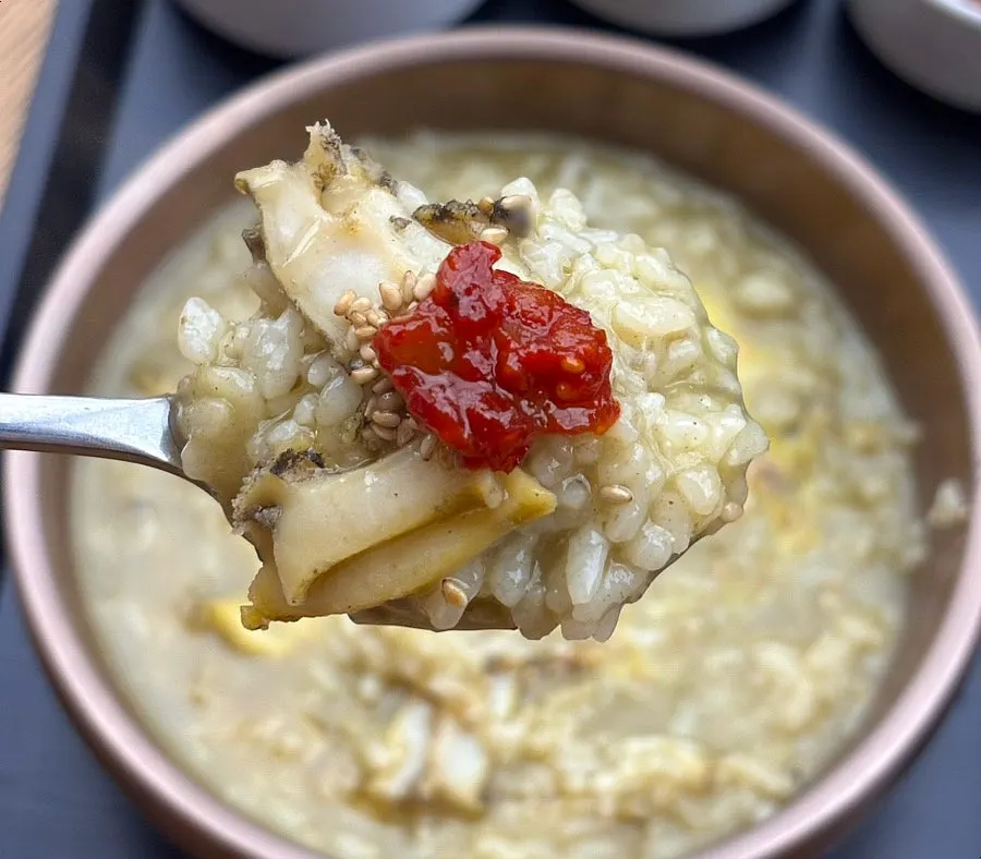 A spoonful of abalone porridge topped with salted seafood