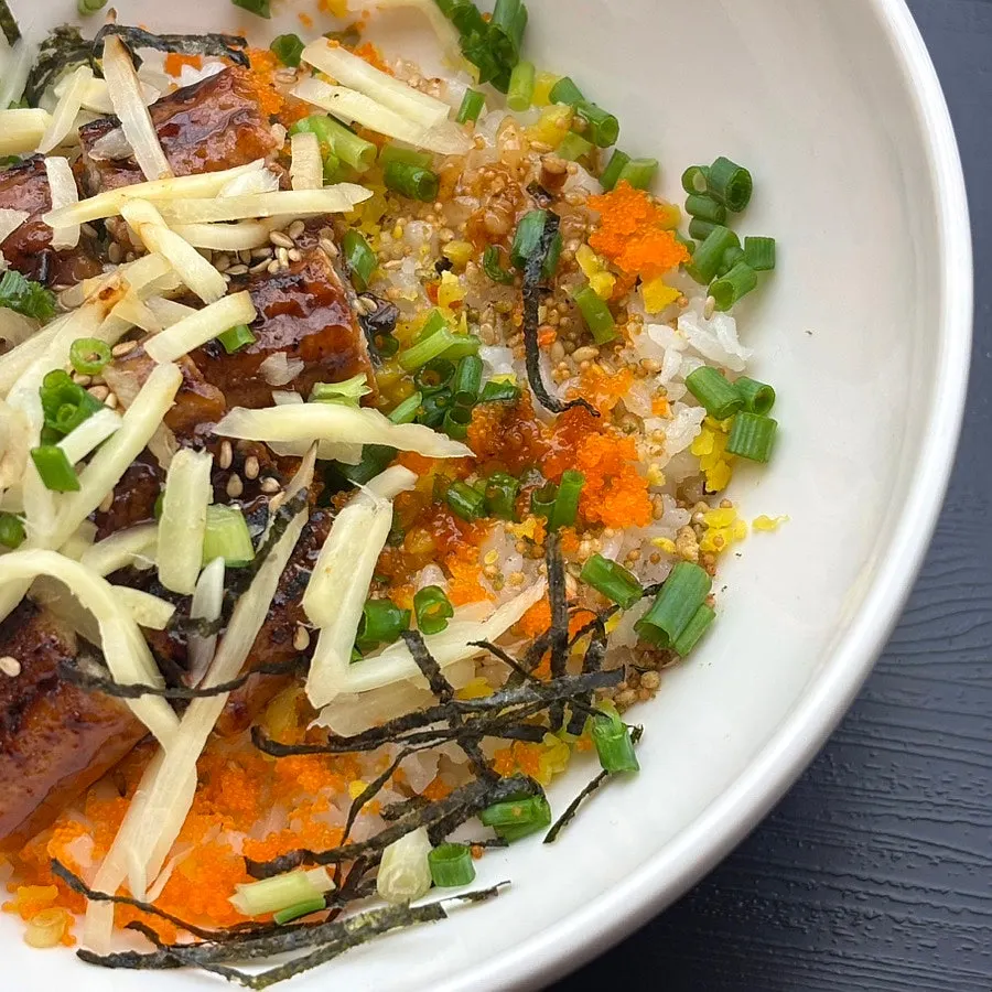 Rice grains topped with flying fish roe, green onion, and seaweed flakes