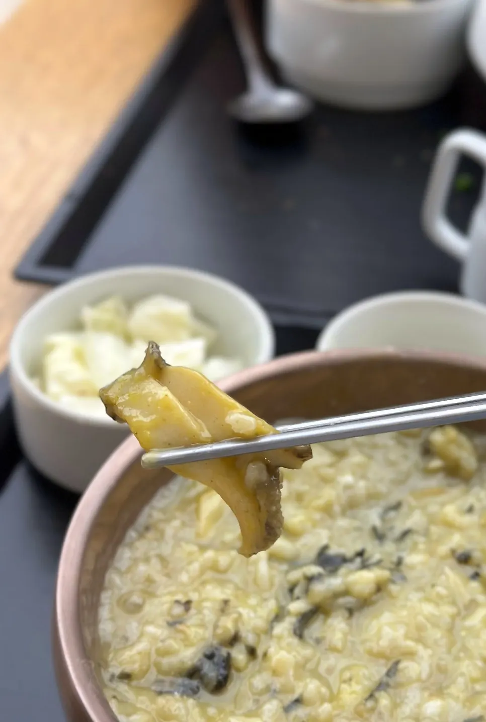 Close-up of abalone porridge topped with egg yolk and gim flakes