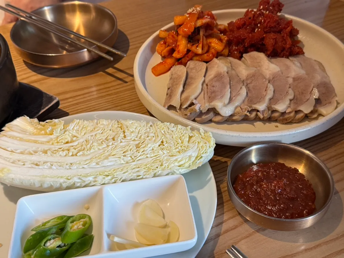 Table spread with pollack sashimi naengmyeon and bossam together