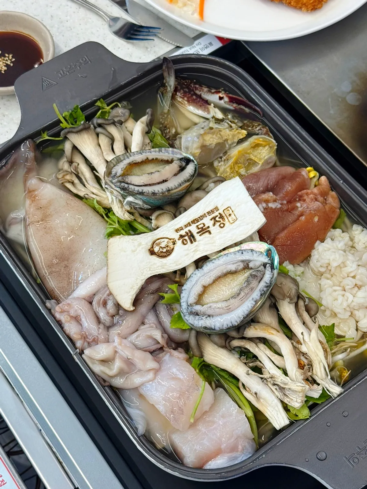 해목정 글자가 찍힌 버섯을 올린 전복해물전골