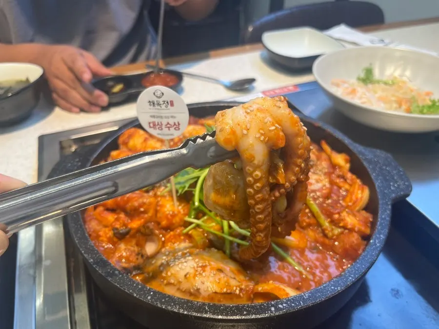 Whole octopus lifted up with tongs