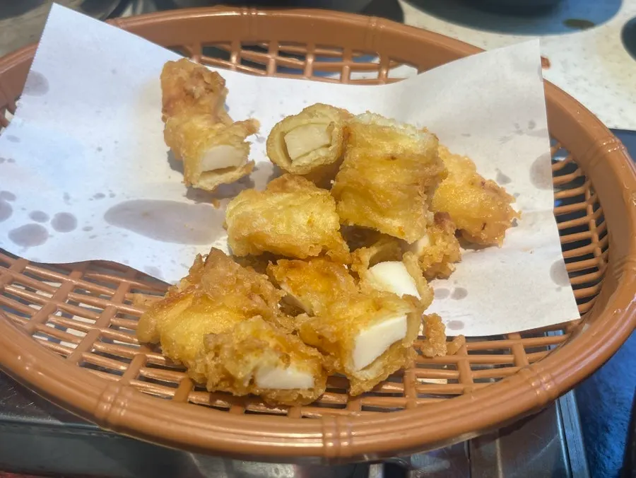 Squid fritter being dipped in seafood galbijjim sauce