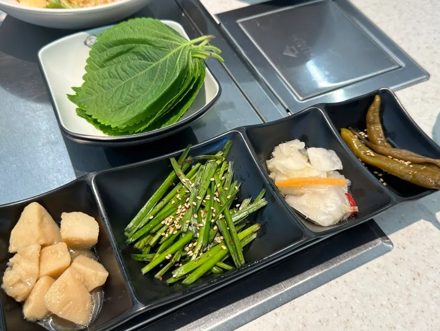 Basic banchan including garlic chives, braised potatoes, and baek-kimchi