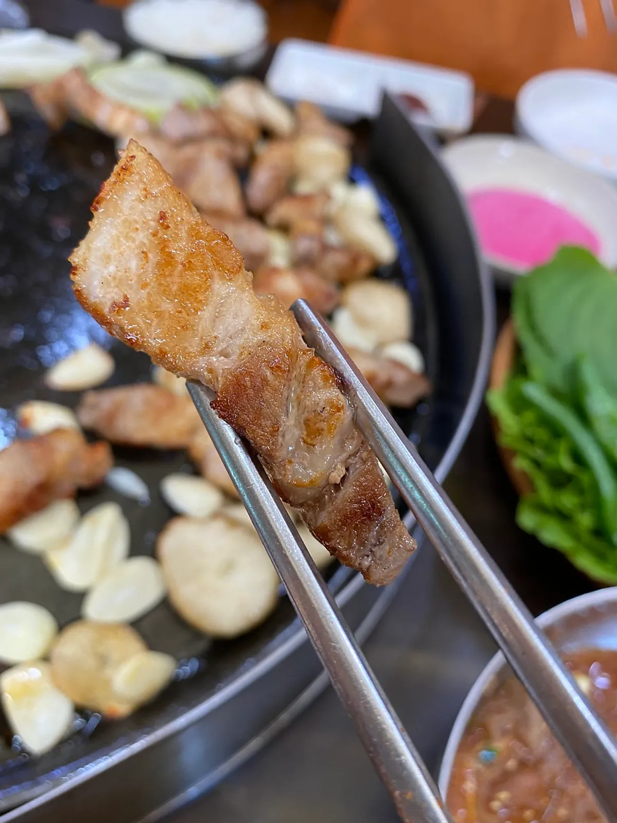 Fresh pork belly grilling on a cauldron lid at Pujutgan Saenggogi-jeom
