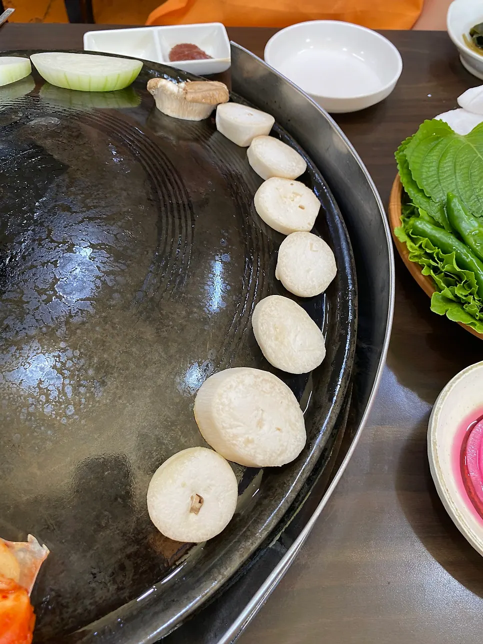 Mushrooms, onion, and potato added to one side of the cauldron lid
