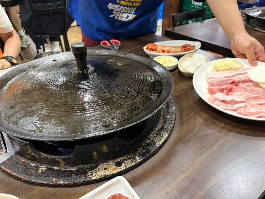 Meat and vegetables grilling on a cauldron lid