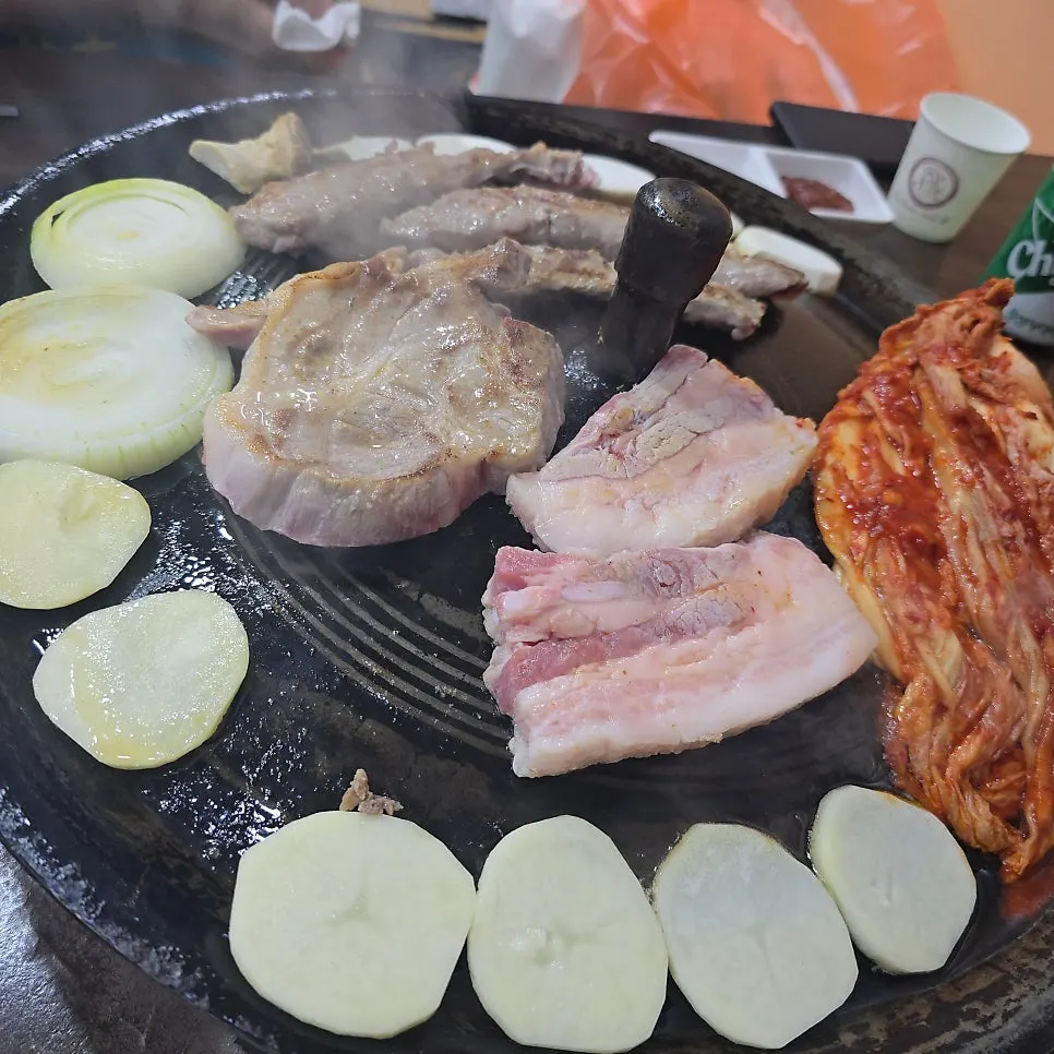 Whole-leaf kimchi and meat grilling on a cauldron lid