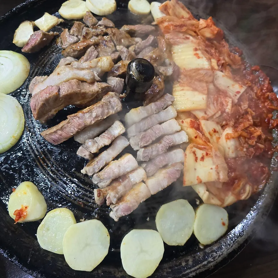 A staff member grilling meat on a cauldron lid