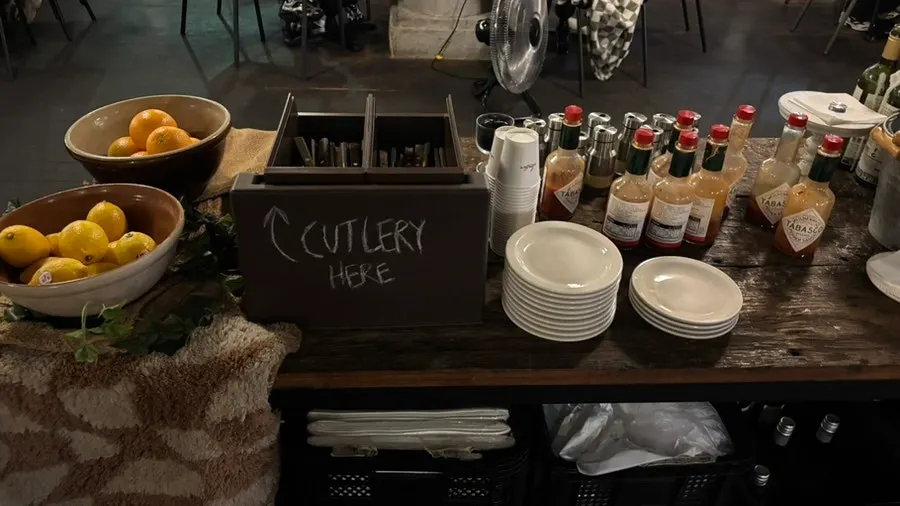 Self-serve bar with hot sauce and parmesan cheese