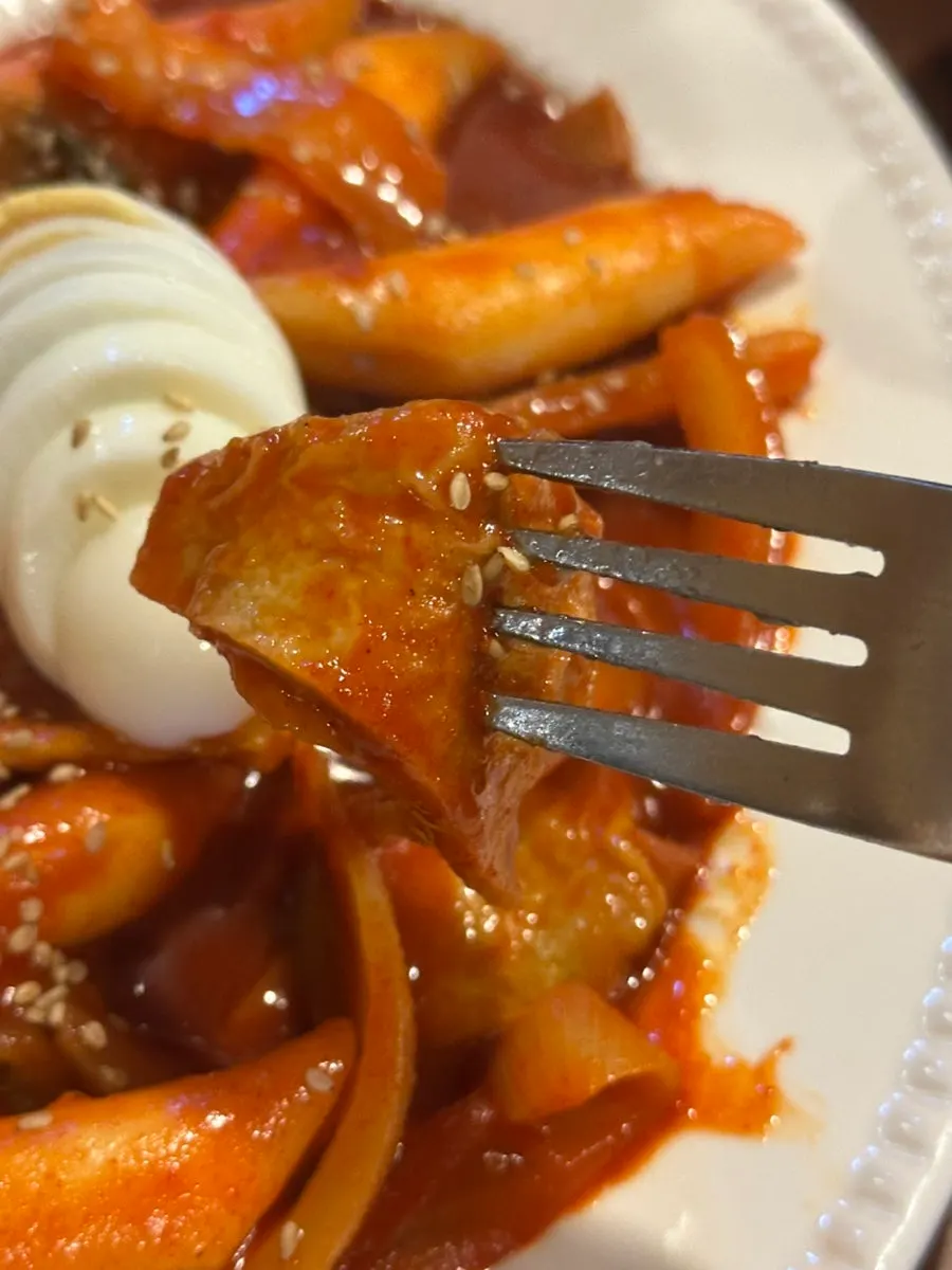 Picking up a piece of rice tteok from the tteokbokki