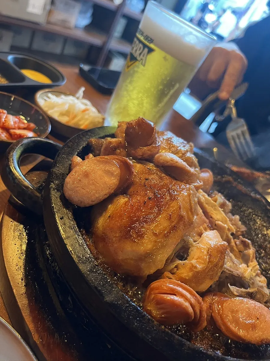 A draft beer glass and chicken on the table
