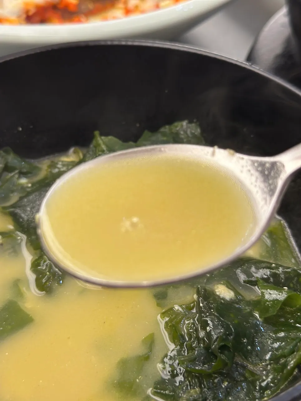 A bowl of seaweed soup topped with a large piece of flounder