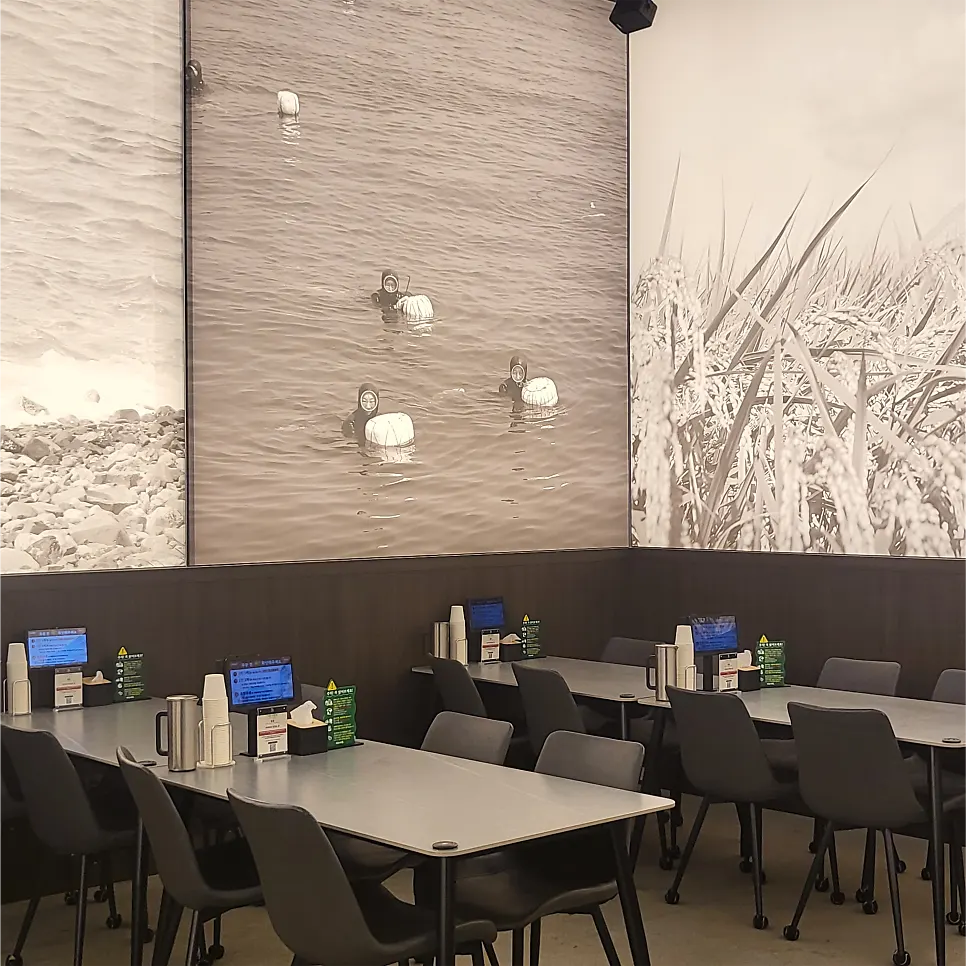 Wall with a black-and-white mural evoking a Jeju seaside scene