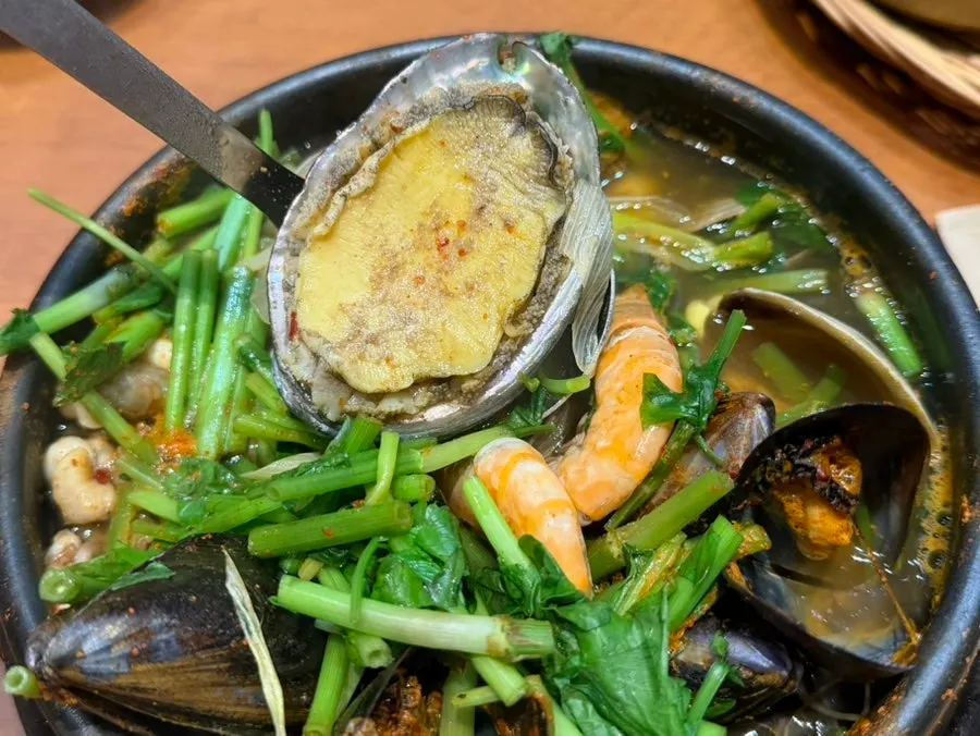 Ladle scooping up ingredients from the seafood stew