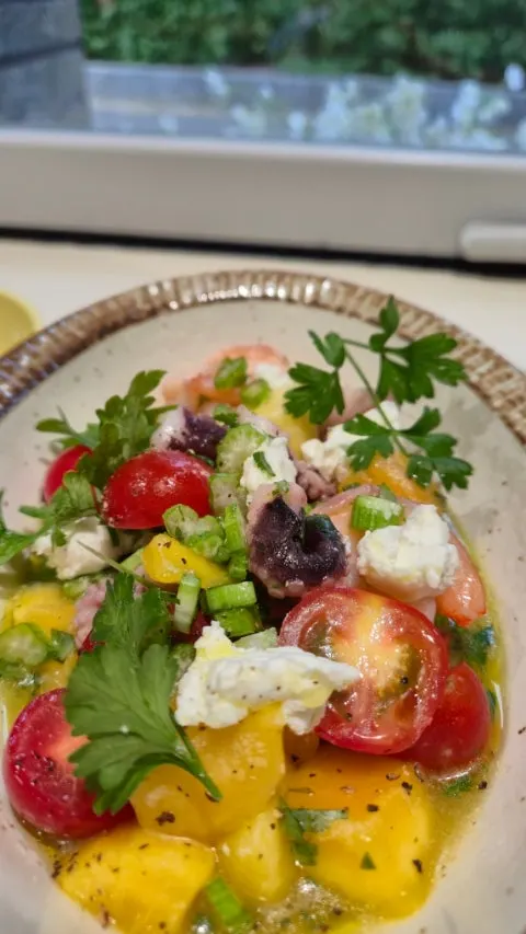 Seafood salad topped with shrimp, cherry tomatoes and ricotta cheese