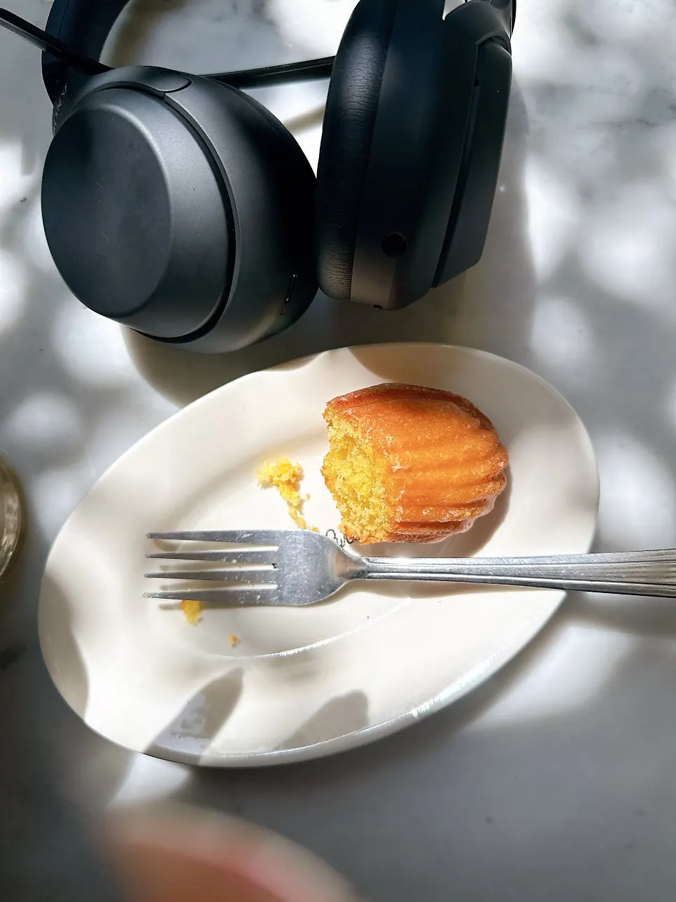 Iced americano and madeleine on a sunlit terrace table