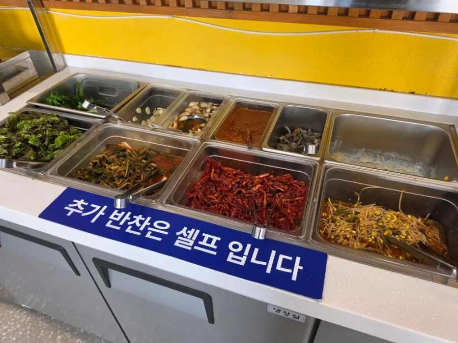 Self-serve side dish bar with lettuce, perilla leaves, and young radish kimchi