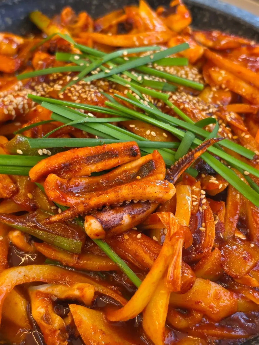Plump squid and green onion cooking on the hot plate