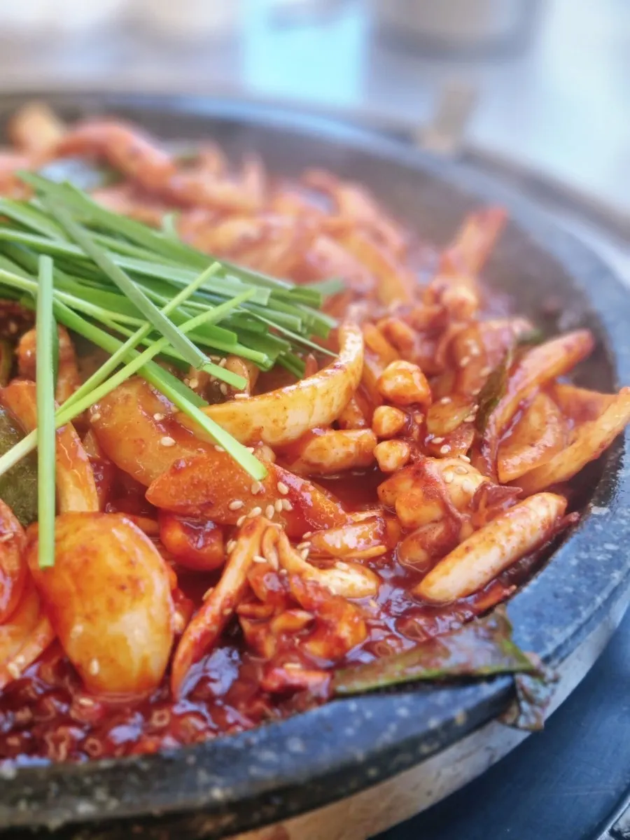 Plump squid in vivid red sauce on the hot plate